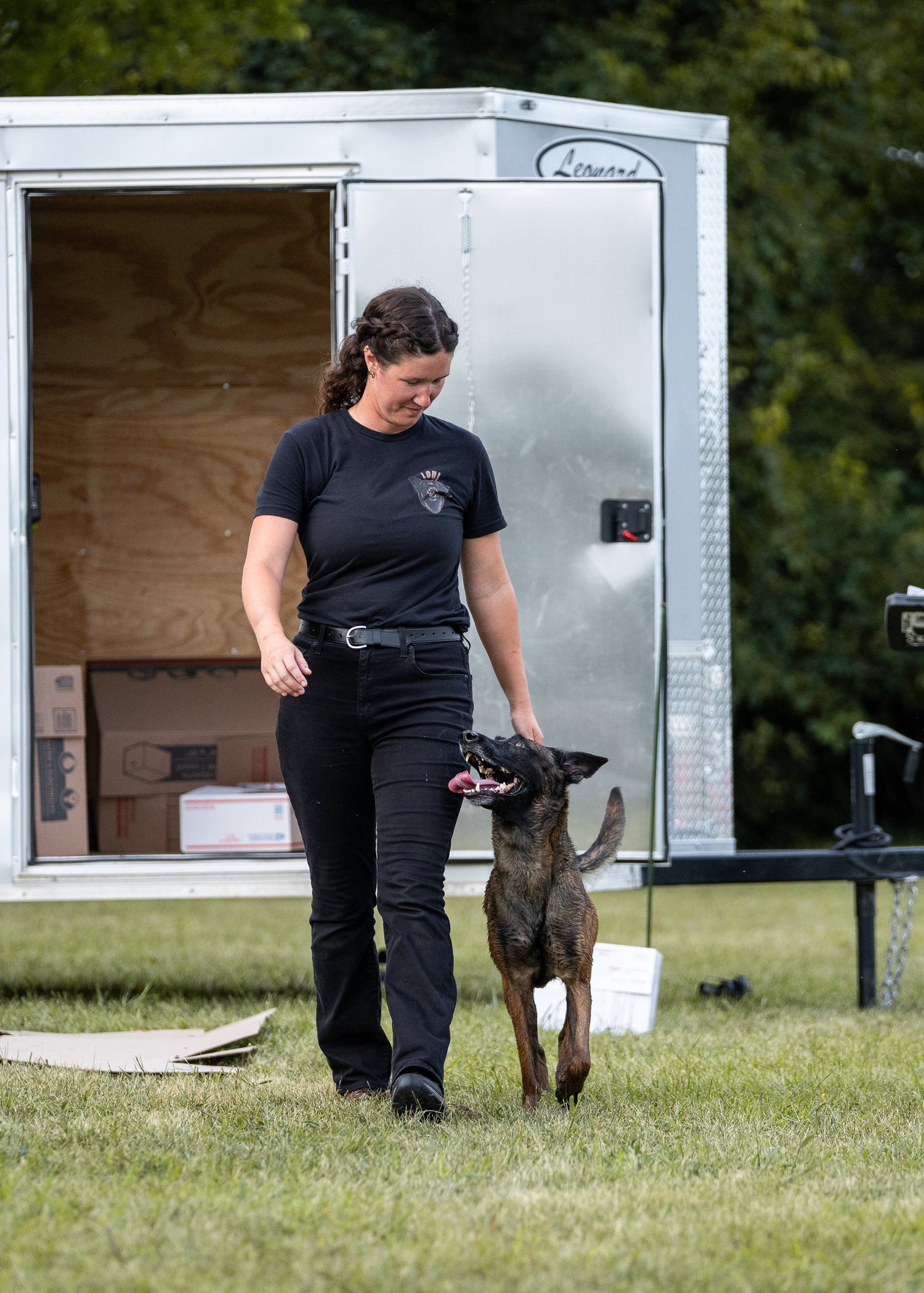 Person with a dog standing next to an open trailer in an outdoor setting